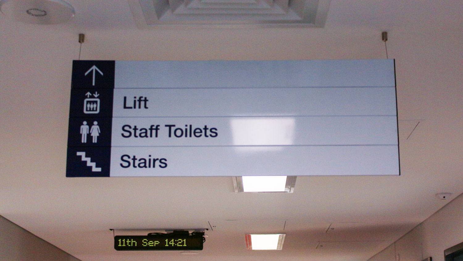 Indoor Directional Sign 2 Hanging From Ceiling Lift And Toilets